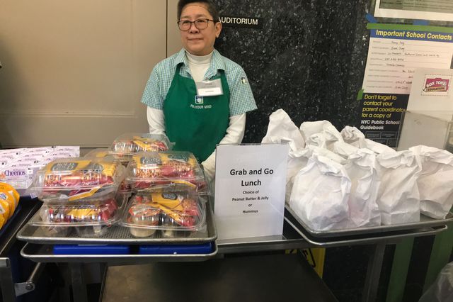 A school staff member stands by a display of food available for any student to pick up at PS 130 in Chinatown.